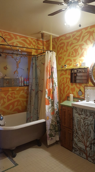 Large clawfoot tub with colorful curtains.