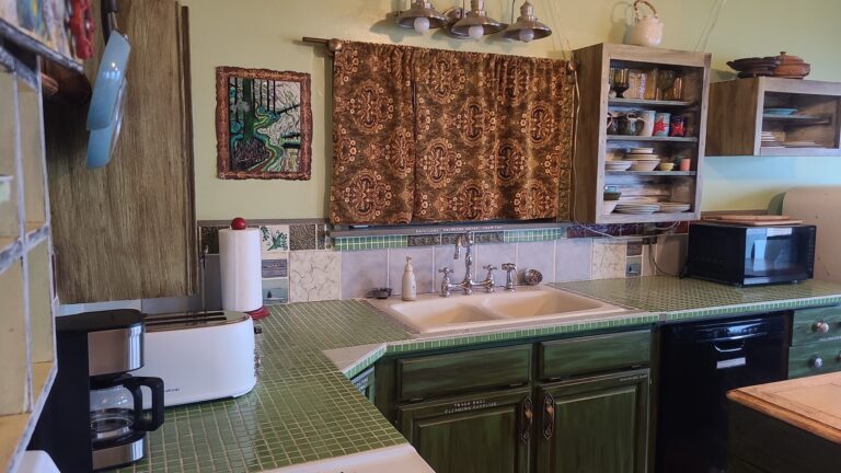 Your full kitchen features vintage green til countertops and a deep porcelain sink.