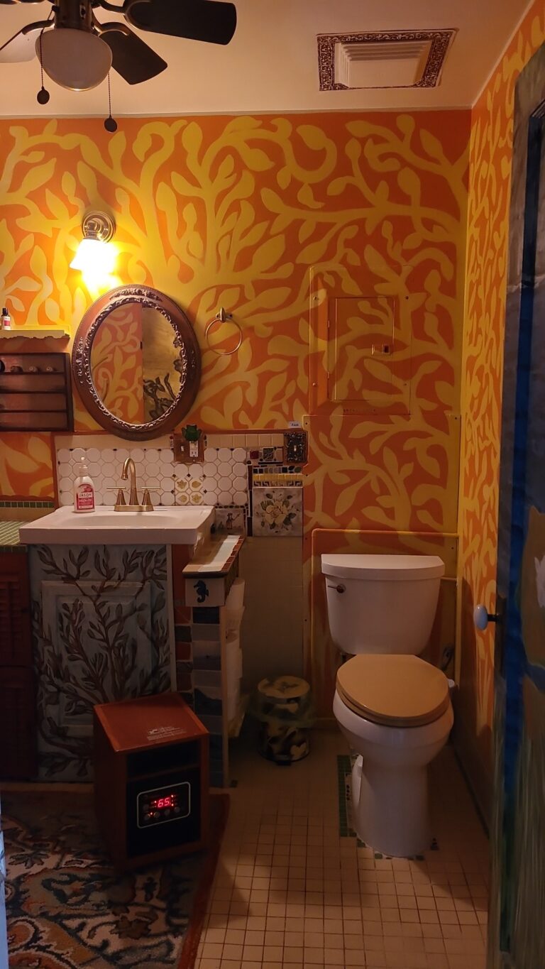 Brightly painted orange and yellow flocked walls give this bathroom with the clawfoot tub a warm and cozy feeling.